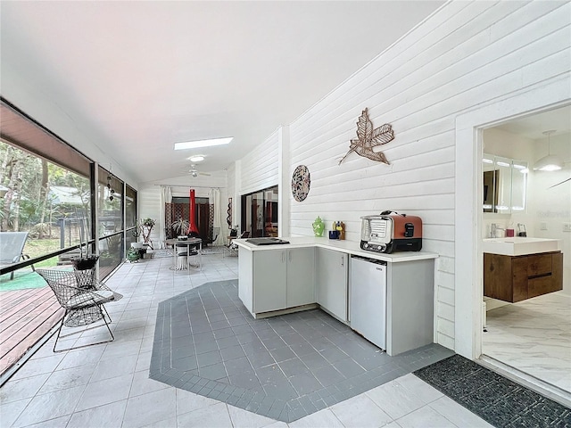 kitchen with light countertops, open floor plan, vaulted ceiling, a sink, and a peninsula