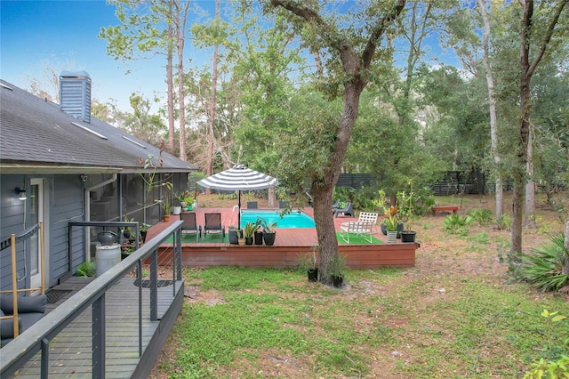 view of yard with a deck, fence, a sunroom, and an outdoor pool