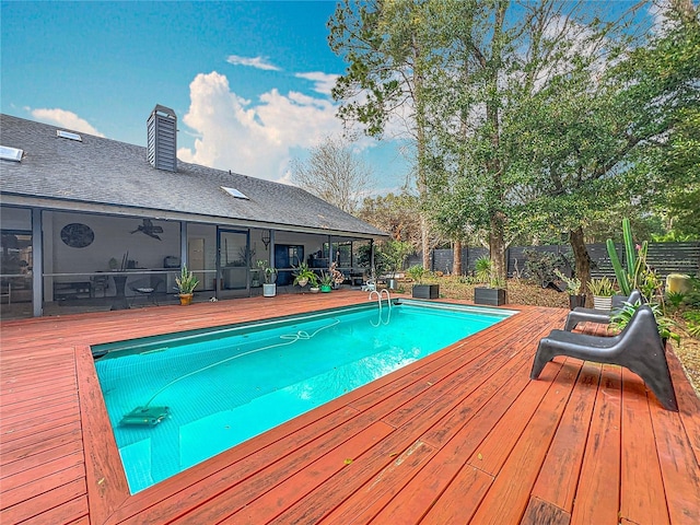 view of pool featuring a fenced in pool, a sunroom, fence, and a wooden deck