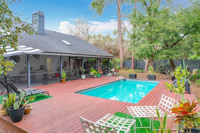 view of swimming pool with a fenced in pool, a sunroom, fence, and a wooden deck