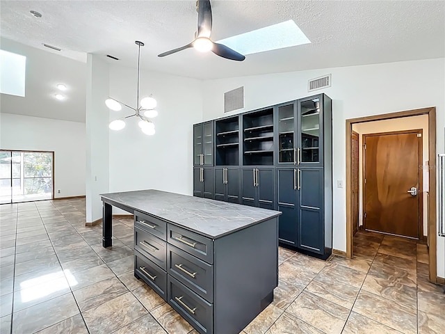 1701 Cedar Stone Ct, Lake Mary, FL 32746 - kitchen with a skylight, a textured ceiling, ceiling fan, baseboards, and a center island