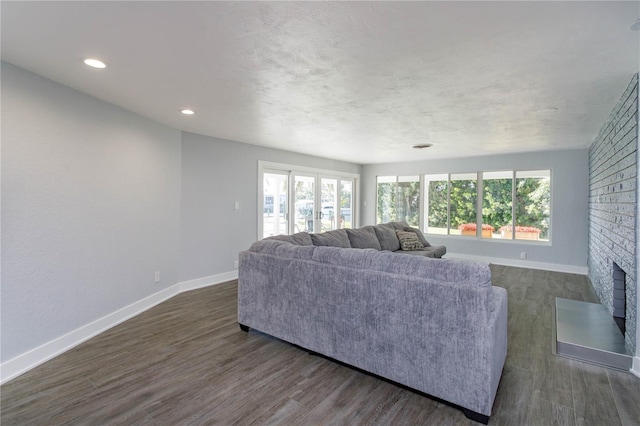 living room featuring dark wood-type flooring and a brick fireplace