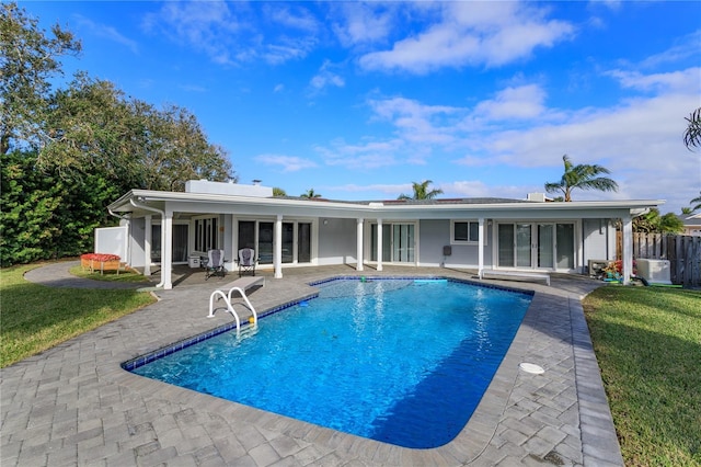 back of property featuring a yard, a fenced in pool, and a patio area