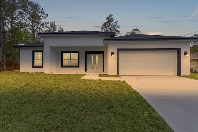 view of front facade with a garage, concrete driveway, a yard, and stucco siding