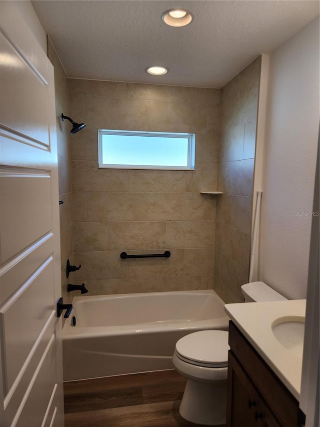 full bathroom with vanity, a textured ceiling, wood-type flooring, toilet, and tiled shower / bath