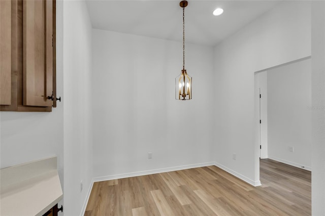 unfurnished dining area with a notable chandelier and light hardwood / wood-style floors