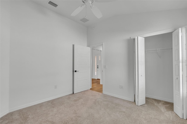 unfurnished bedroom featuring vaulted ceiling, light colored carpet, ceiling fan, and a closet