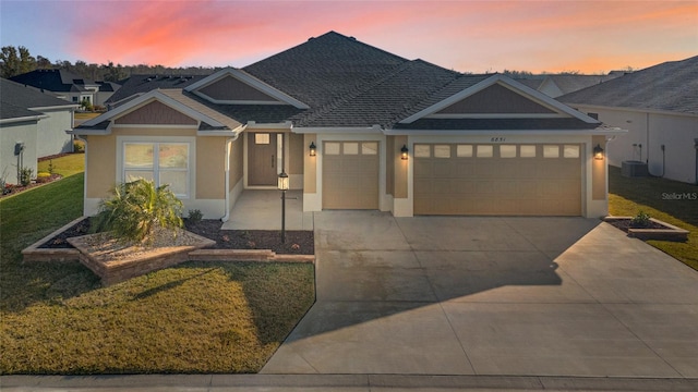 view of front of house with a garage, a lawn, and central air condition unit