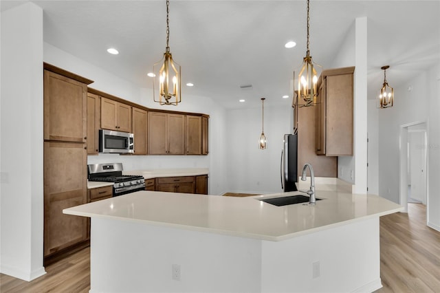 kitchen featuring sink, decorative light fixtures, light hardwood / wood-style flooring, and appliances with stainless steel finishes