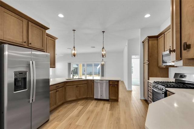 kitchen with appliances with stainless steel finishes, sink, hanging light fixtures, kitchen peninsula, and light wood-type flooring