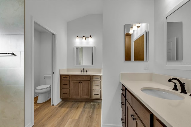 bathroom featuring hardwood / wood-style flooring, vanity, vaulted ceiling, and toilet