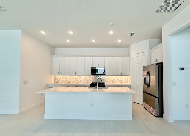 kitchen featuring appliances with stainless steel finishes, an island with sink, white cabinetry, and sink