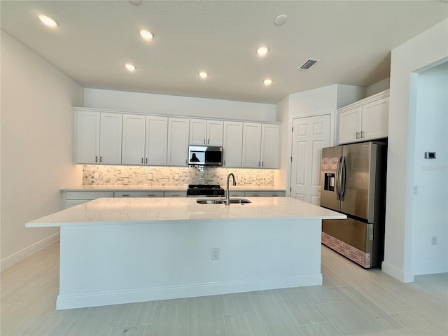 kitchen featuring white cabinets, stainless steel appliances, a kitchen island with sink, and sink