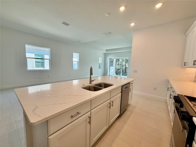 kitchen featuring light stone countertops, sink, a center island with sink, dishwasher, and range