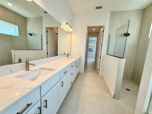 bathroom with tile patterned floors, vanity, and a tile shower