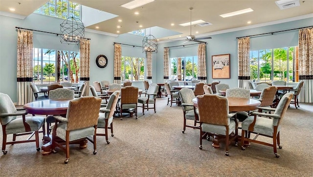 carpeted dining area featuring ceiling fan with notable chandelier, plenty of natural light, and crown molding