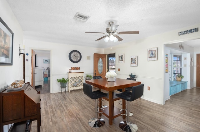 dining area featuring ceiling fan, a textured ceiling, and dark wood-type flooring