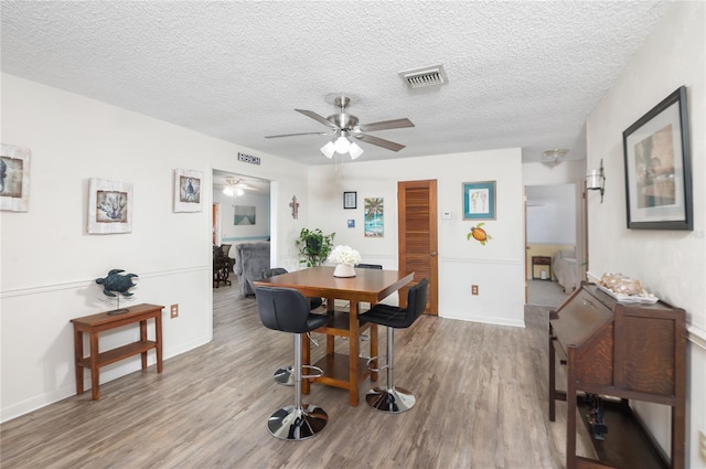 dining room featuring a textured ceiling, light hardwood / wood-style flooring, and ceiling fan