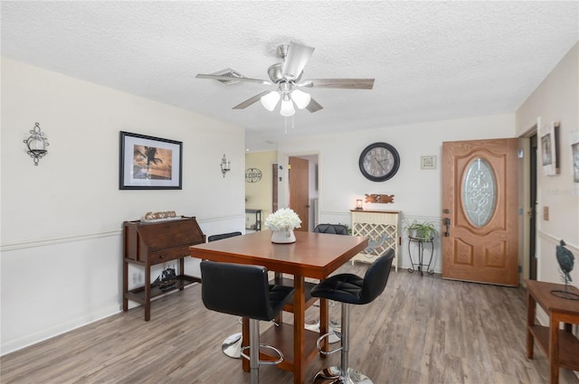 dining room with ceiling fan, wood-type flooring, and a textured ceiling