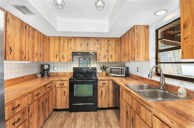 kitchen featuring wood counters, sink, black appliances, and light hardwood / wood-style flooring