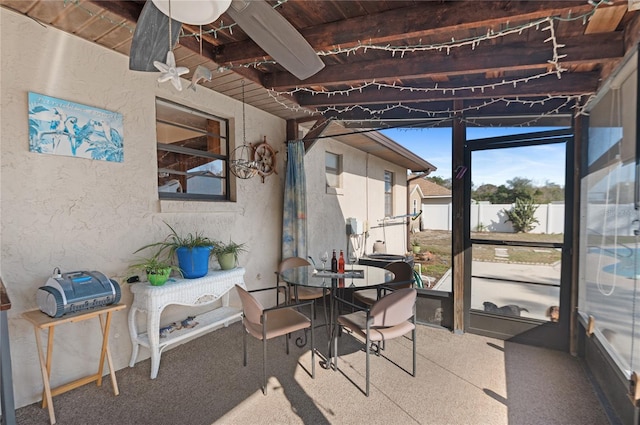 sunroom featuring beamed ceiling and a healthy amount of sunlight