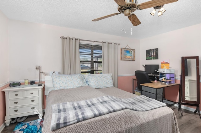 bedroom with hardwood / wood-style floors, ceiling fan, and a textured ceiling