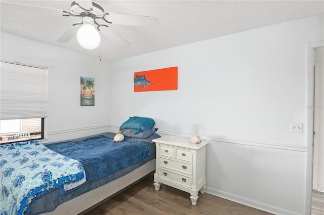 bedroom featuring ceiling fan, dark wood-type flooring, and a textured ceiling