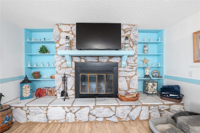 room details featuring built in features, a textured ceiling, and a stone fireplace