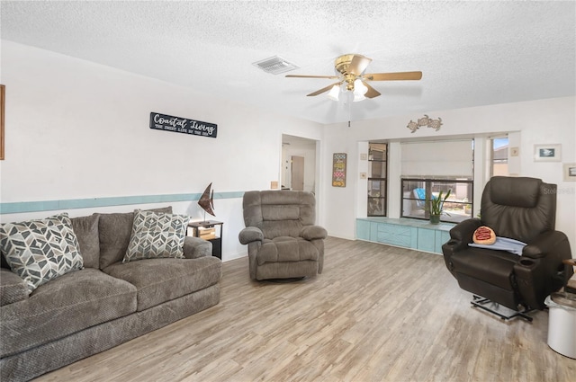 living room featuring hardwood / wood-style floors, ceiling fan, and a textured ceiling