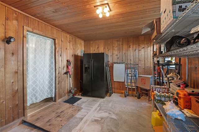 kitchen with black refrigerator with ice dispenser, wooden ceiling, and wood walls