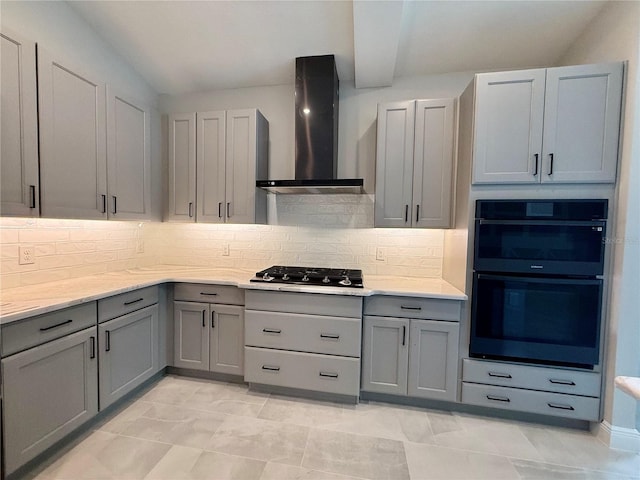 kitchen featuring backsplash, wall chimney exhaust hood, black double oven, stainless steel gas cooktop, and gray cabinets