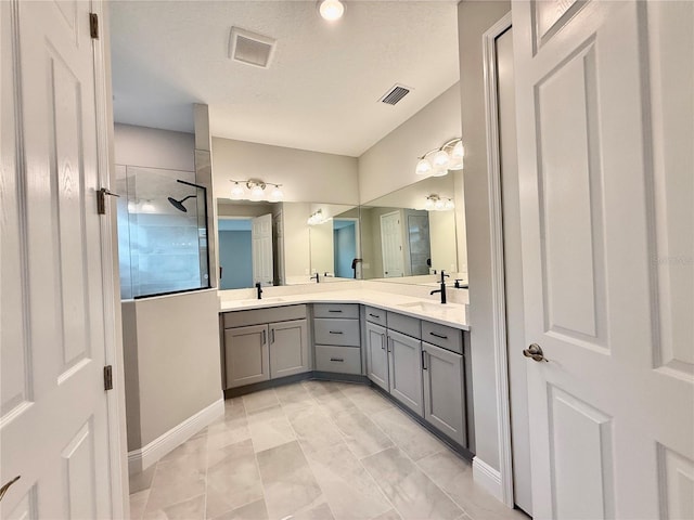 bathroom with a textured ceiling, vanity, tiled shower, and tile patterned flooring