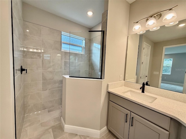 bathroom featuring tile patterned flooring, a tile shower, and vanity