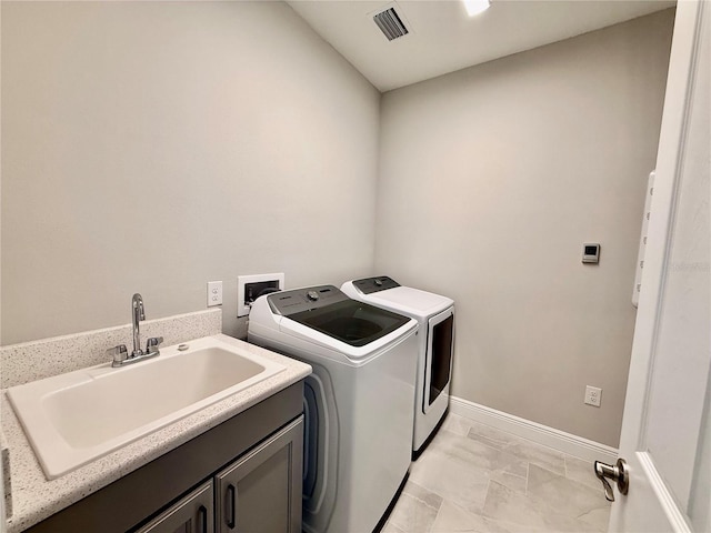 washroom featuring cabinets, light tile patterned floors, washing machine and dryer, and sink