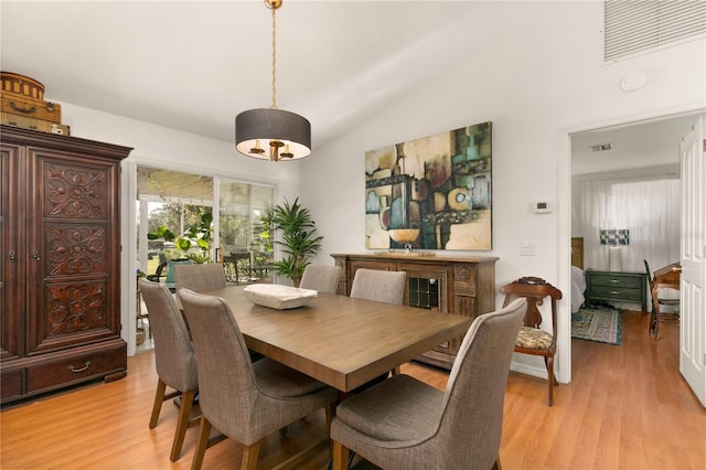 dining space with vaulted ceiling and light hardwood / wood-style floors