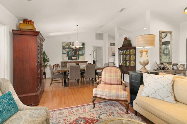 living area featuring visible vents, lofted ceiling, and wood finished floors