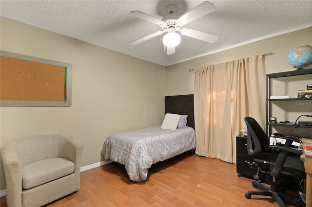 bedroom with ceiling fan, wood-type flooring, and a textured ceiling