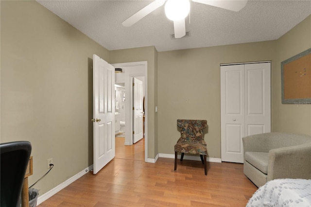 bedroom featuring ceiling fan, a textured ceiling, light hardwood / wood-style floors, and a closet