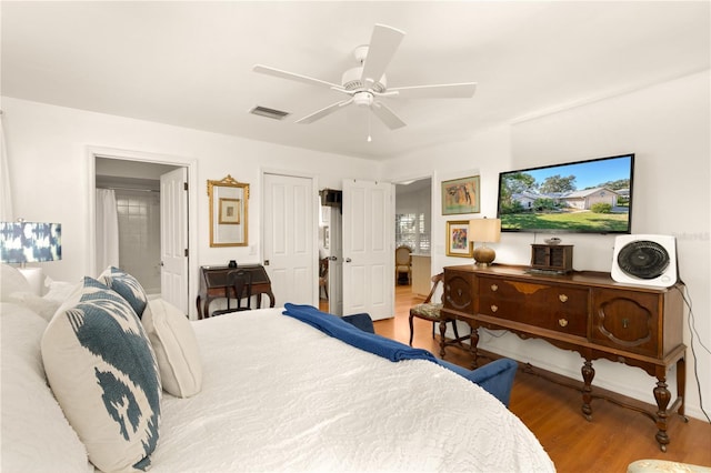 bedroom with visible vents, ensuite bath, ceiling fan, and wood finished floors