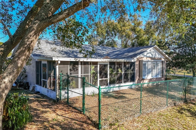 back of house featuring stucco siding, a sunroom, roof with shingles, and fence