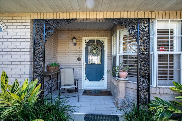 entrance to property with covered porch and brick siding