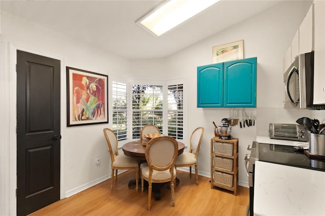 dining area with baseboards, light wood-style flooring, and a toaster