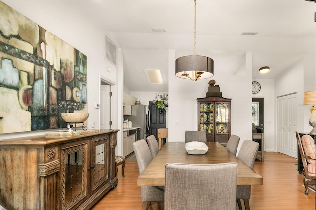 dining area with visible vents, light wood-type flooring, and lofted ceiling