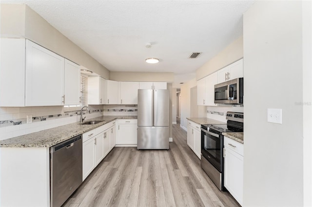 kitchen featuring white cabinets, light stone countertops, sink, and appliances with stainless steel finishes