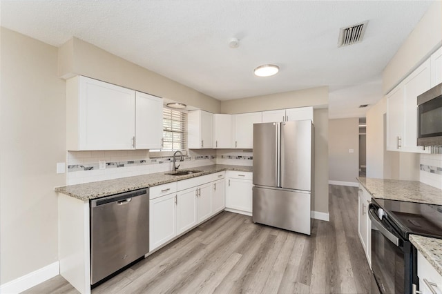 kitchen featuring tasteful backsplash, light stone counters, stainless steel appliances, sink, and white cabinetry