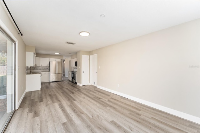 unfurnished living room with light hardwood / wood-style floors and sink