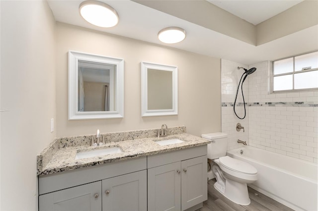 full bathroom with hardwood / wood-style flooring, vanity, toilet, and tiled shower / bath combo