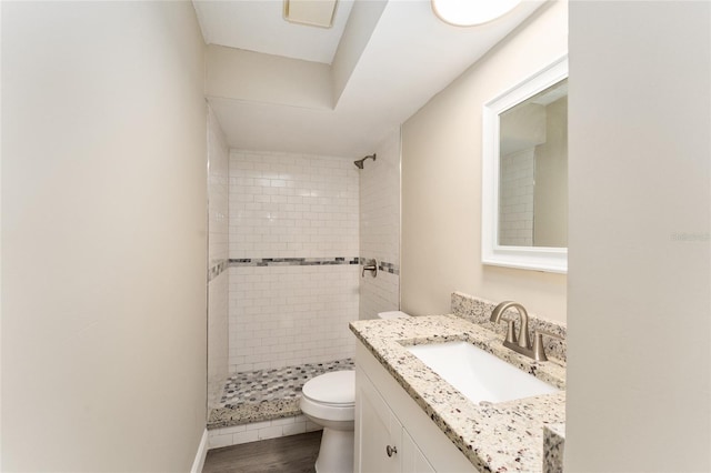 bathroom featuring tiled shower, wood-type flooring, vanity, and toilet