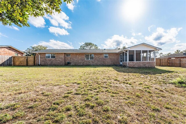 back of property featuring a sunroom and a yard