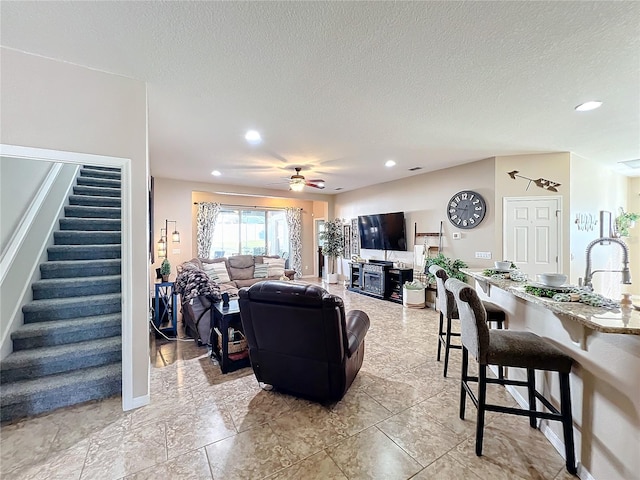 living room featuring ceiling fan and a textured ceiling